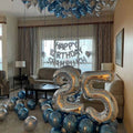 Living room decorated with silver and blue balloons, including a 'Happy Birthday Shahrukh' banner.