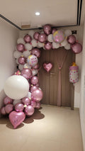 Balloon arch with pink and white balloons in a room.