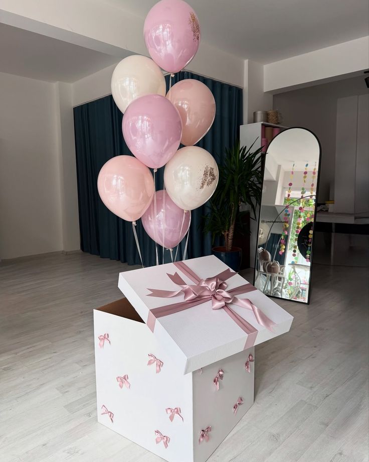 Decorative box with pink ribbon and balloons in a room setting
