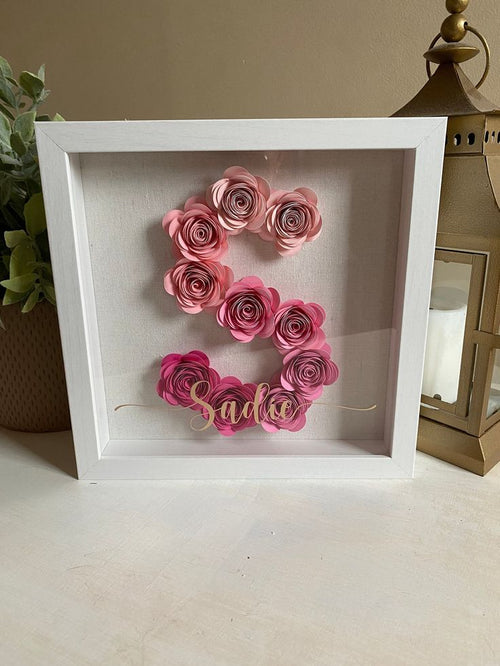 White shadow box with pink floral letter 'S' and name 'Sasha' on a neutral background