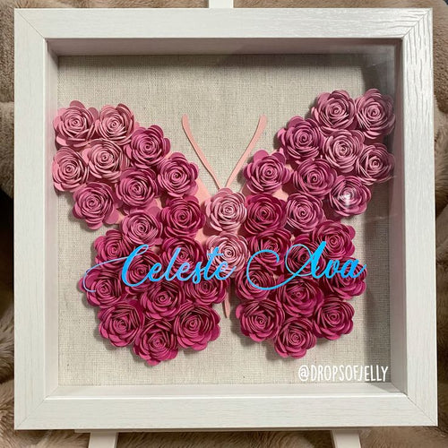 Butterfly-shaped art made of pink roses with 'Celeste & Ava' in the center, framed in white.