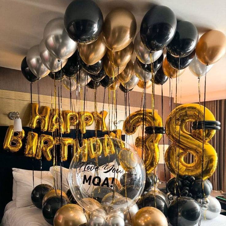 Birthday balloon setup with 'Happy Birthday' and number '28' on a bed.