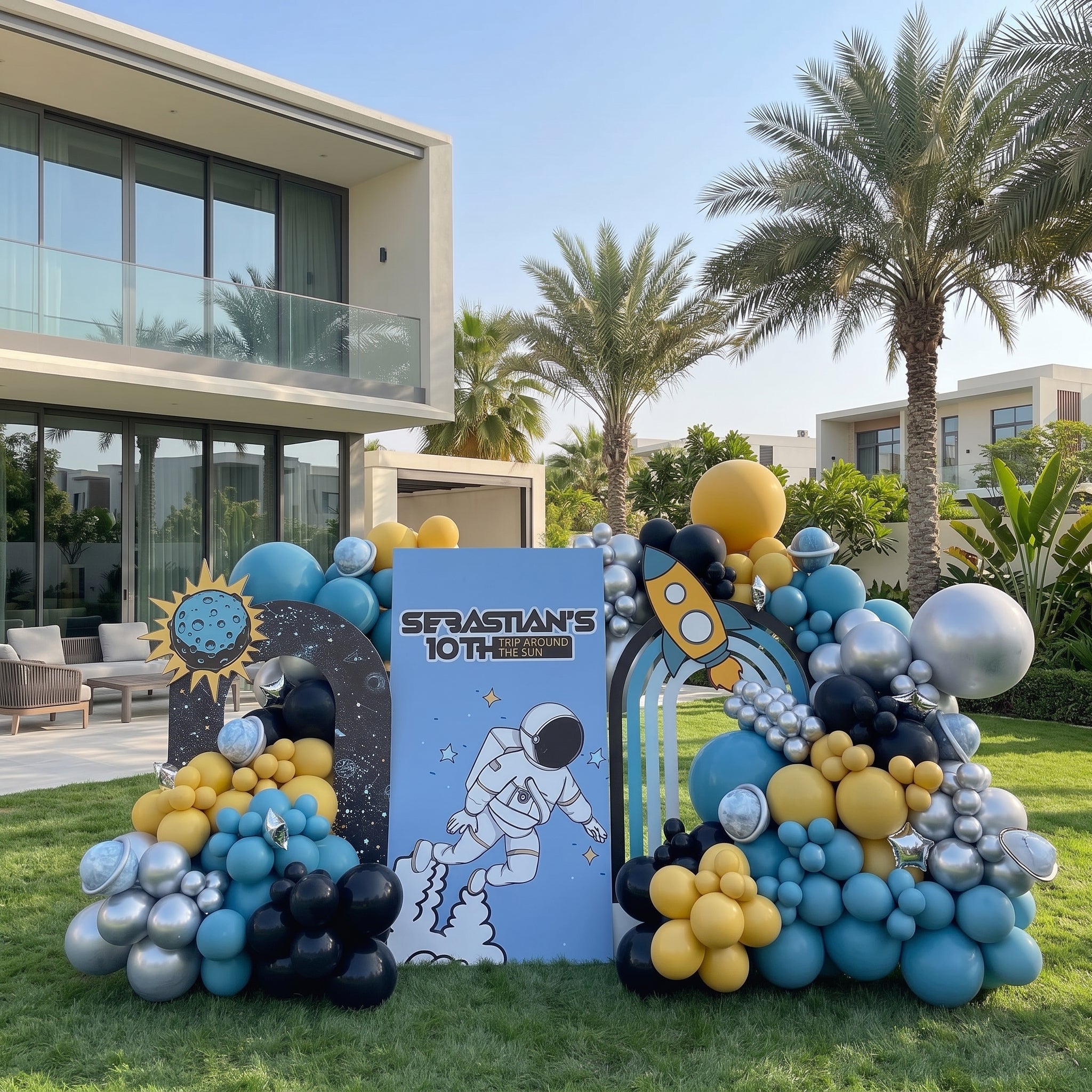 Outer space themed Trip Around the Sun birthday backdrop in Dubai with astronaut board, rocket arch, and blue, yellow, and chrome balloon garland.
